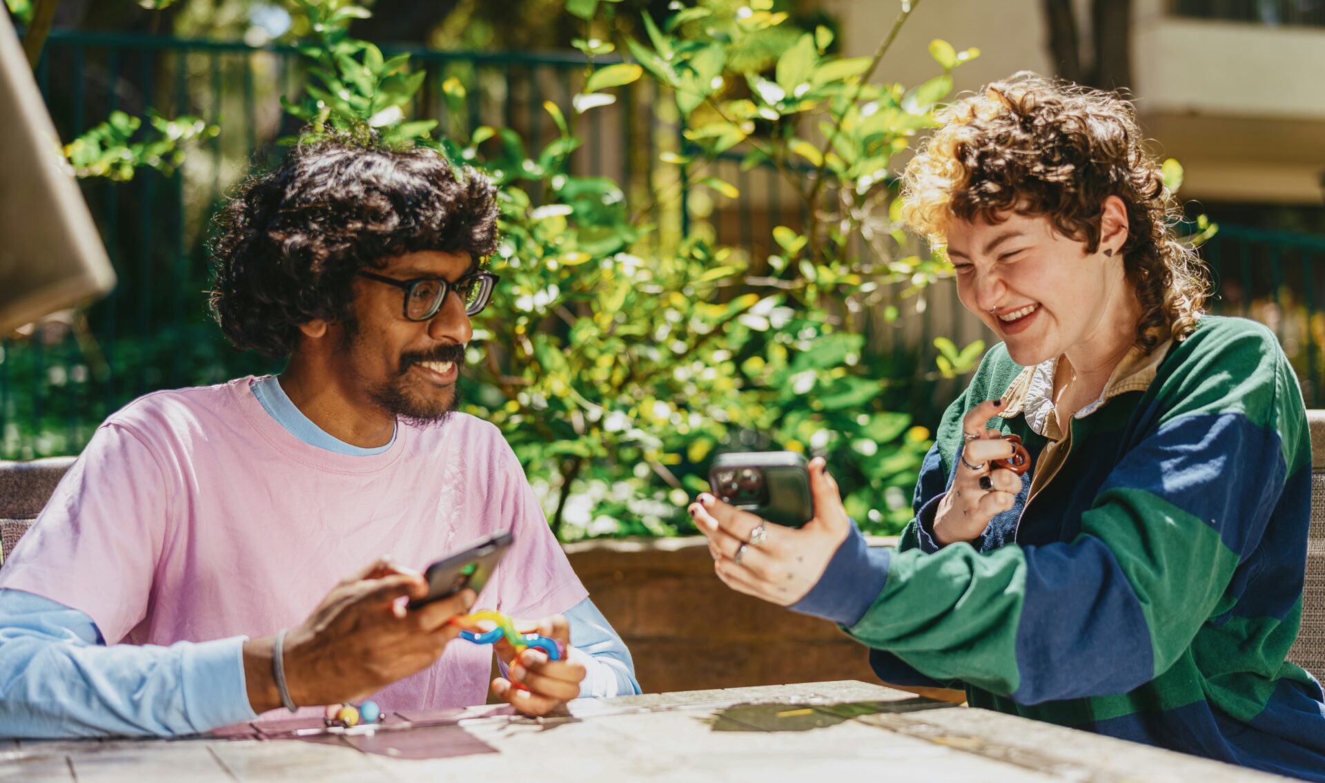 Two autistic young adults laughing over a phone