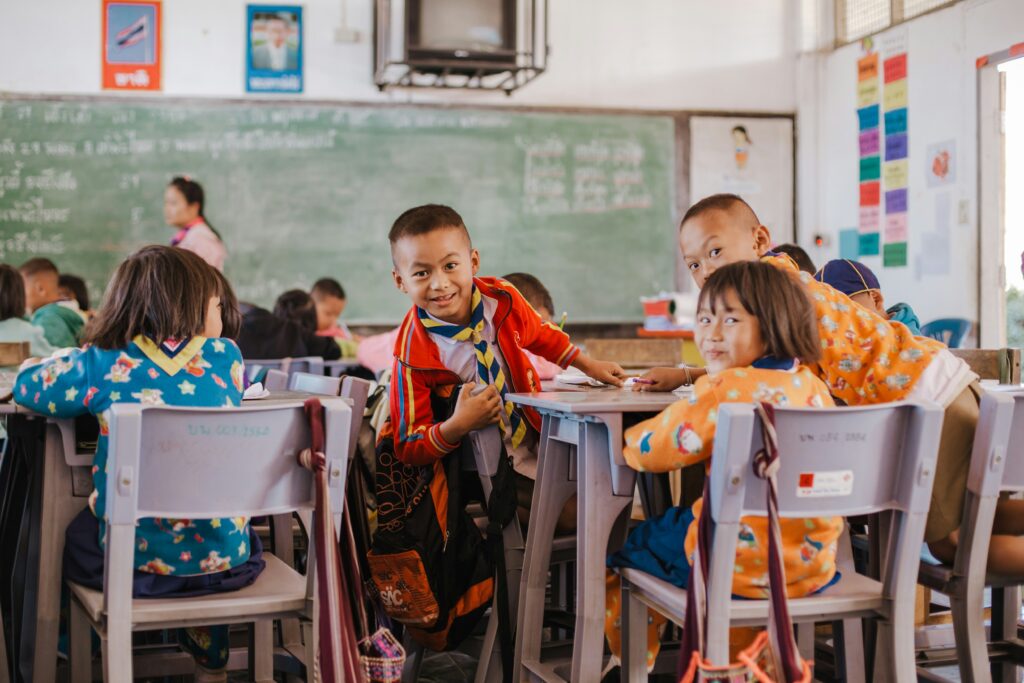 Students smile at camera in a classroom