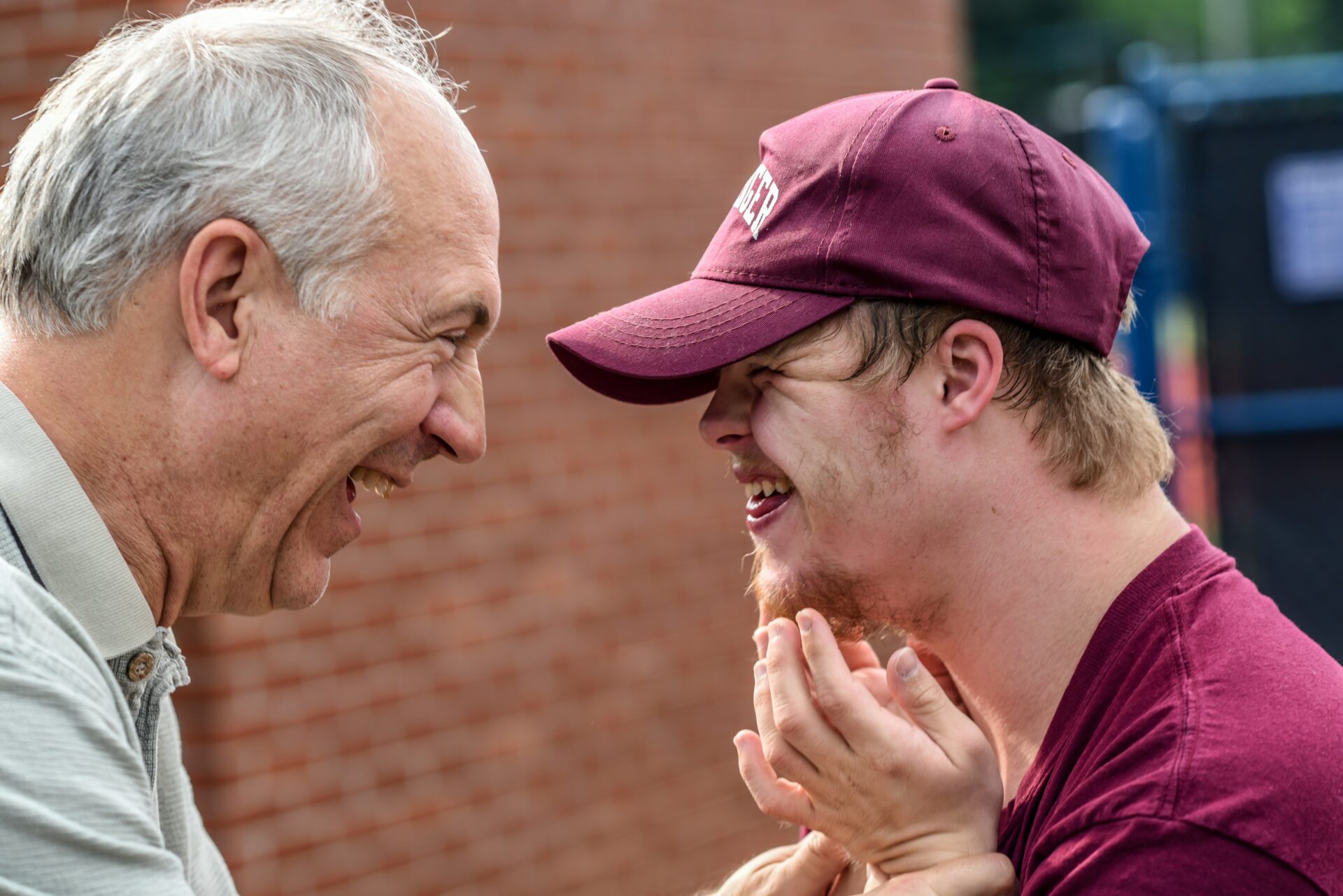 A grandfather and grandson with Down Syndrome laugh together.
