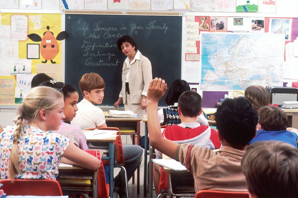 A child raises his hand in a classroom.