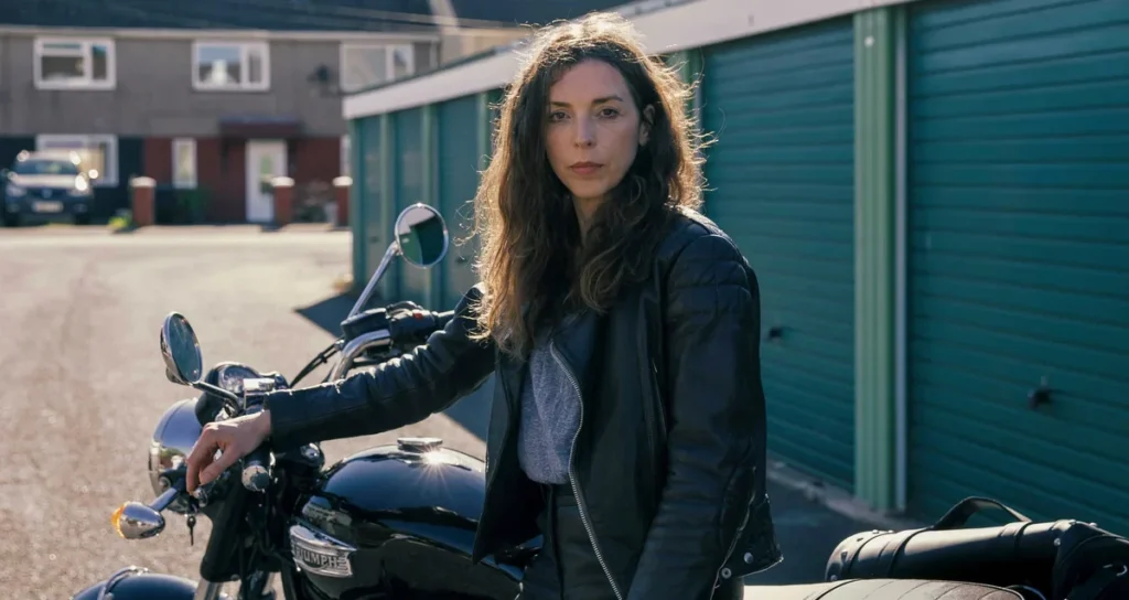 Linda from The Change looks at the camera from atop a motorcycle.