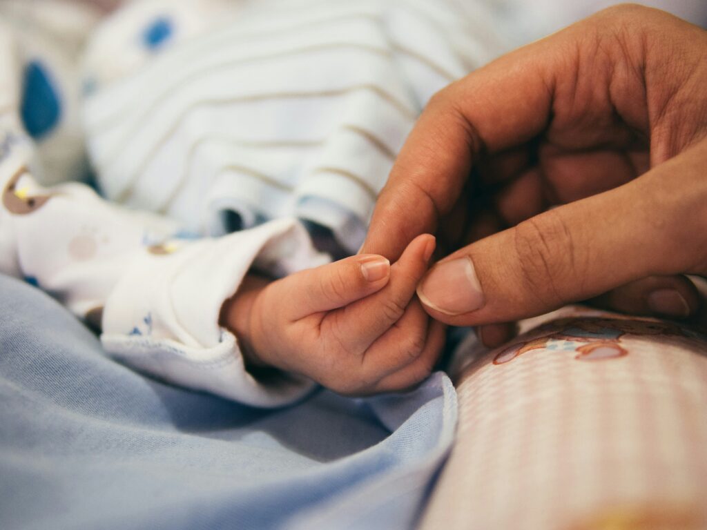A parent holds the finger of their newborn baby.