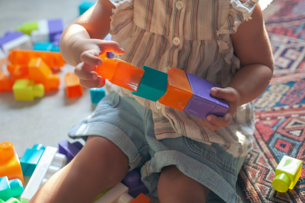 A toddler plays with colorful building blocks.