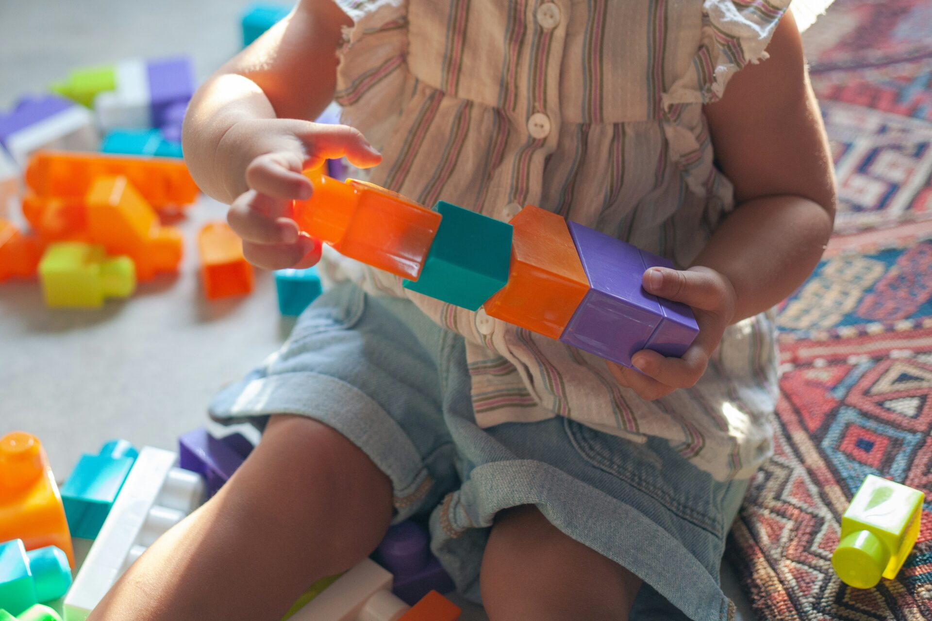 A toddler plays with colorful building blocks.