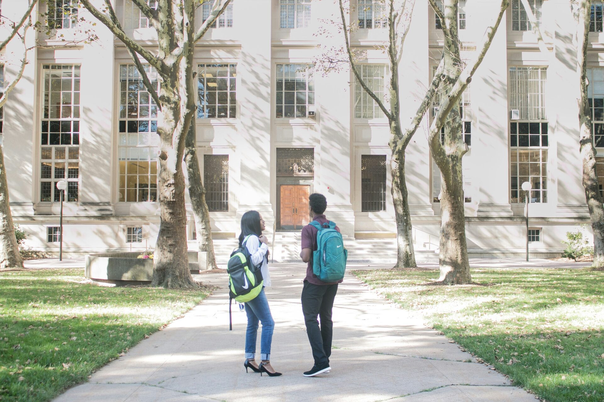 Two students converse outside a college building.