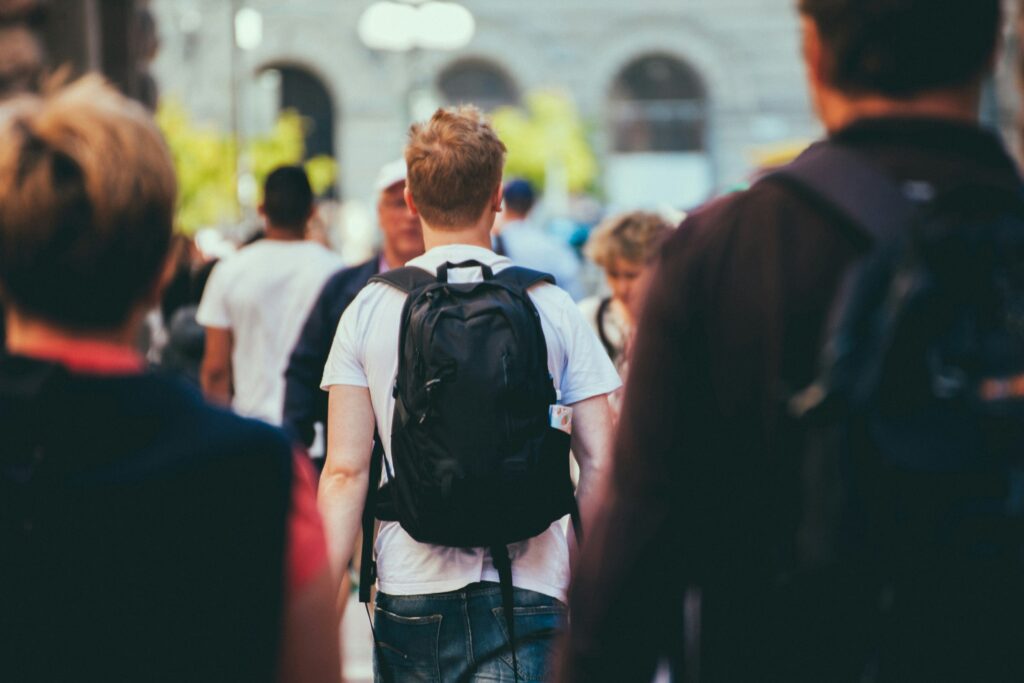 A student crosses a street while carrying a backpack.
