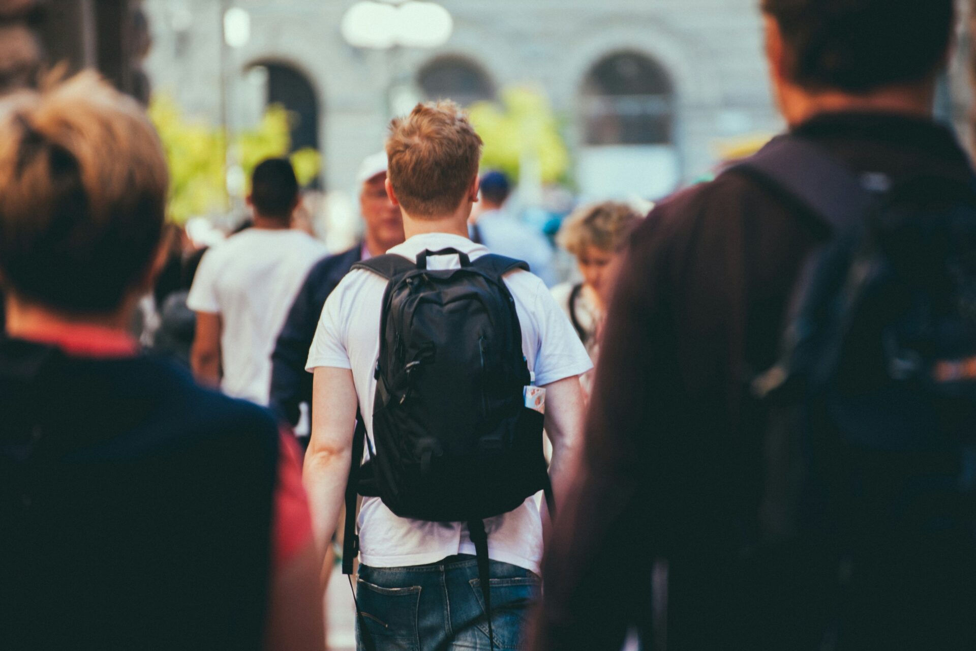 A student crosses a street while carrying a backpack.