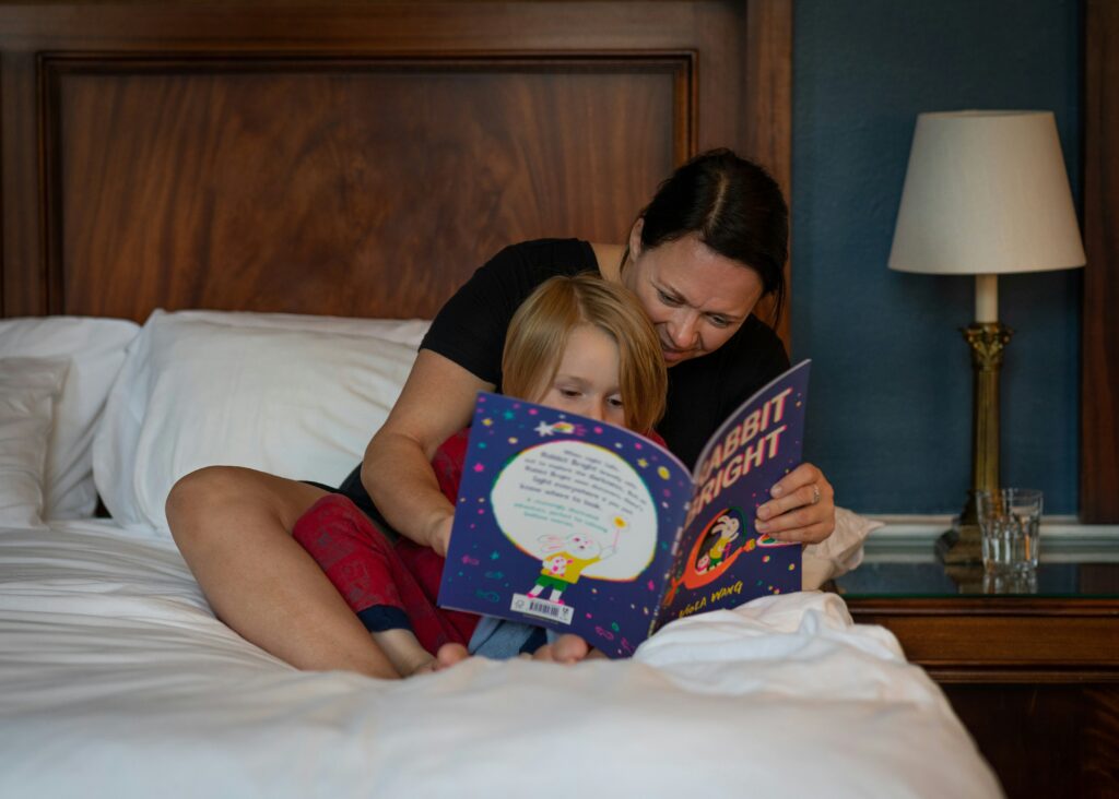 A mom and her son read a picture book together in bed.