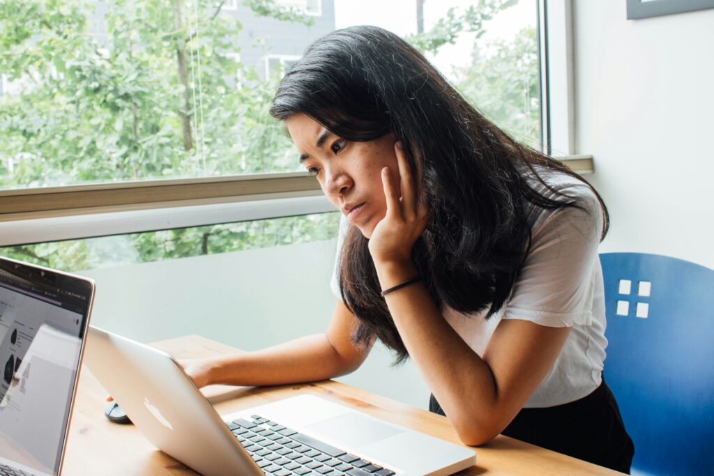 A woman stares at her laptop screen, confused.