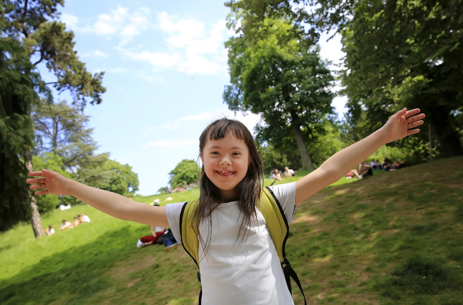 A child smiles with her hands in the air.